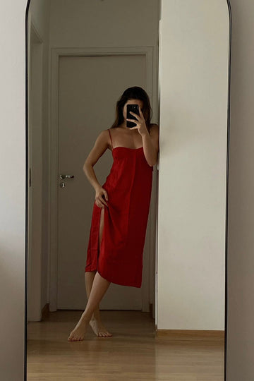 Vestido curto vermelho com busto estruturado, fenda lateral e alças finas.